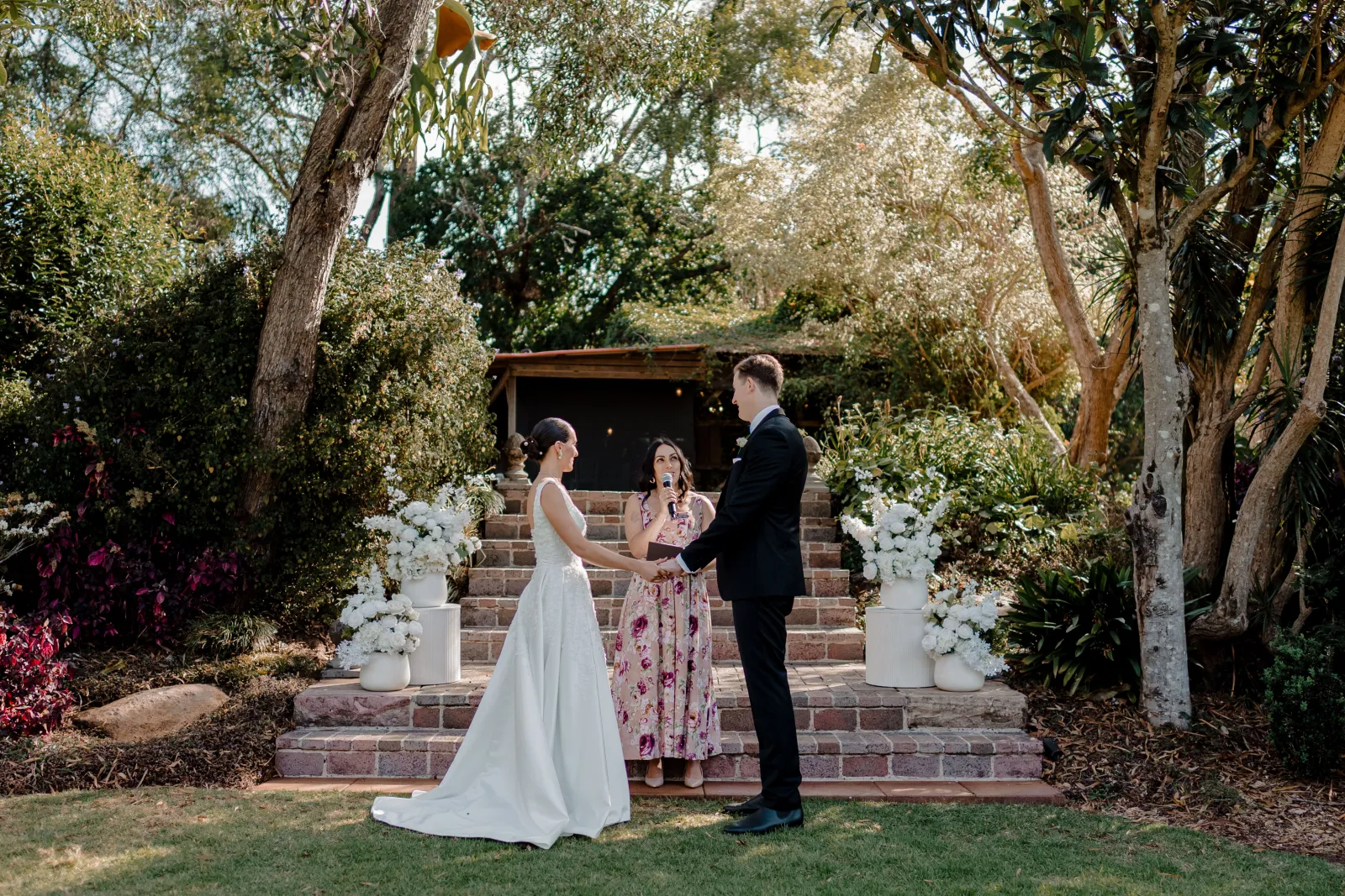 Ellie officiating a personalised garden wedding ceremony with the couple holding hands