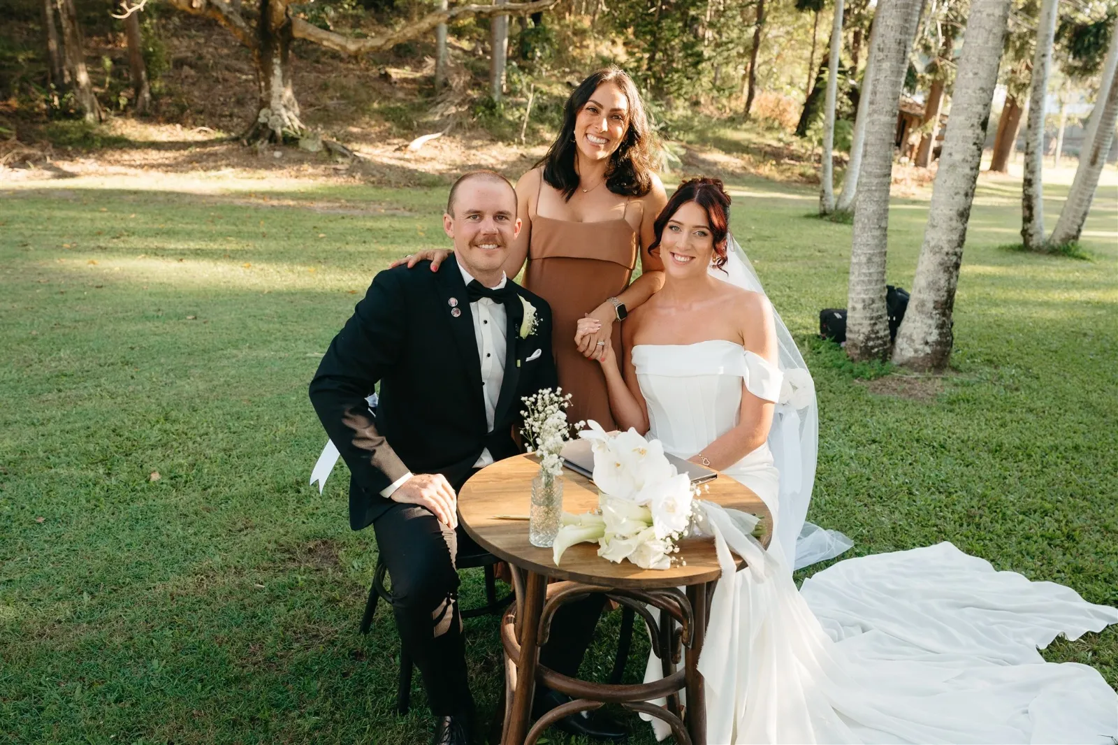 Bride and groom signing the marriage certificate with Ellie celebrating in a garden setting