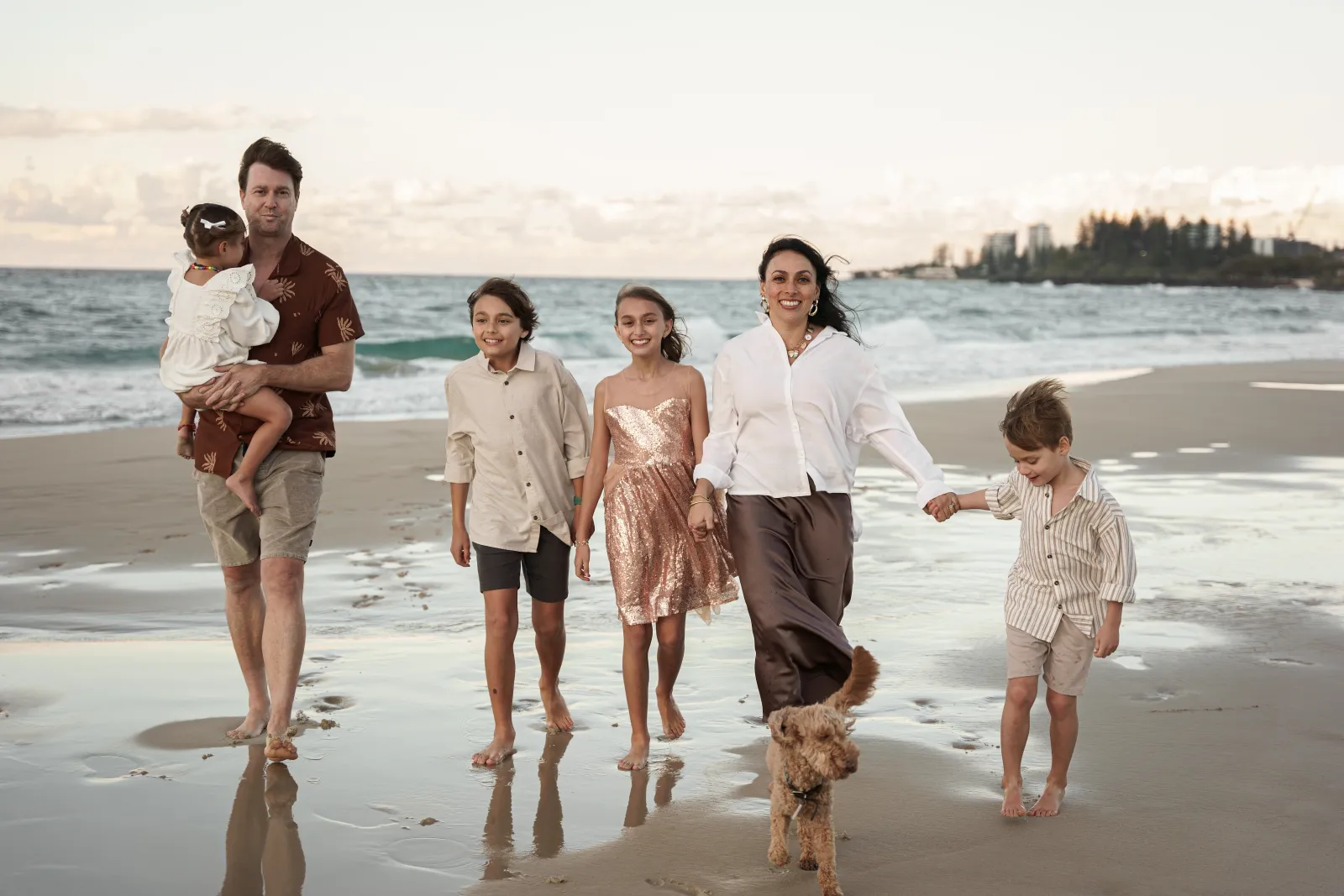 Ellie Smyth, marriage celebrant, walking on a Gold Coast beach with her husband, four children and dog at golden hour